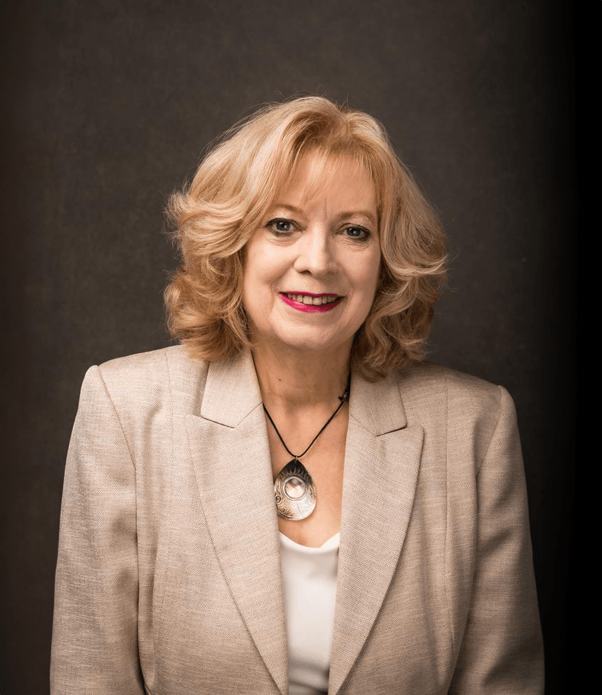 Professional portrait of a confident woman in a beige blazer.